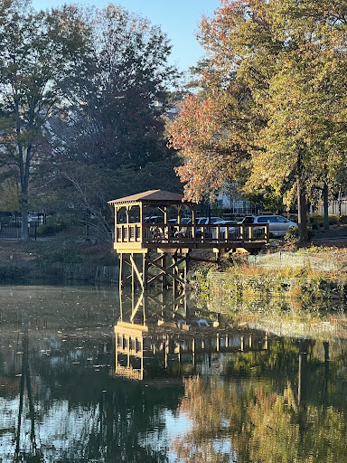 A serene lakeside view featuring a wooden dock surrounded by autumn foliage.