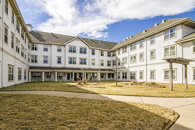 A large residential building with a well-maintained lawn under a partly cloudy sky.