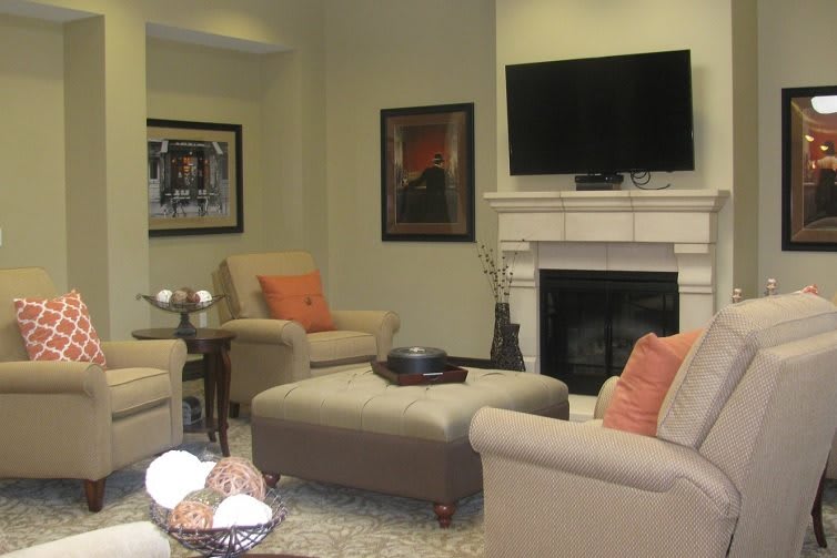 A cozy living room with neutral-toned furniture, a wall-mounted television, and a fireplace.