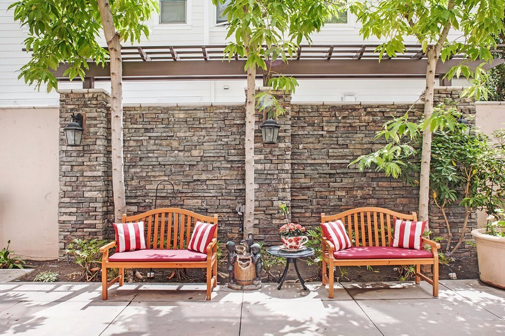 A cozy patio setup with two wooden benches and red striped cushions in a garden setting.