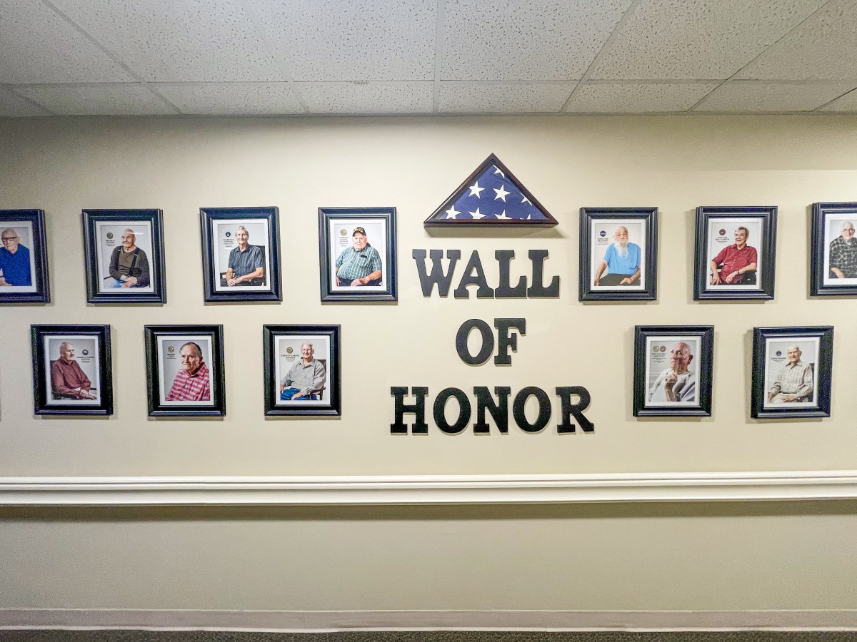 A Wall of Honor showcasing portraits of veterans, featuring a folded flag and the words 'WALL OF HONOR'.