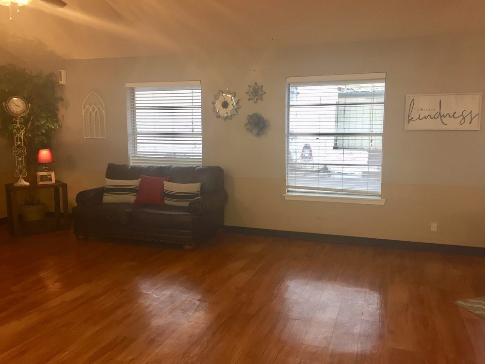 A cozy living room with a couch, wooden floors, and natural light from windows.