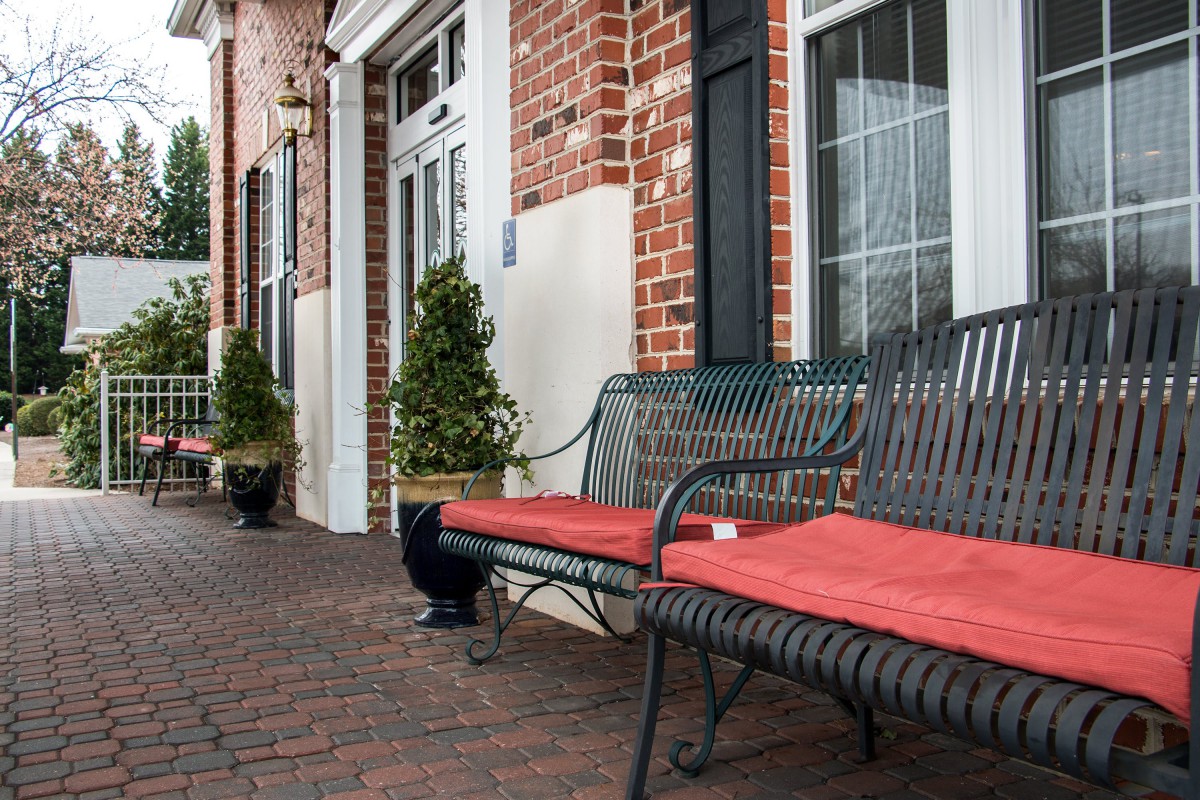 Outdoor benches with red cushions in front of a brick building.