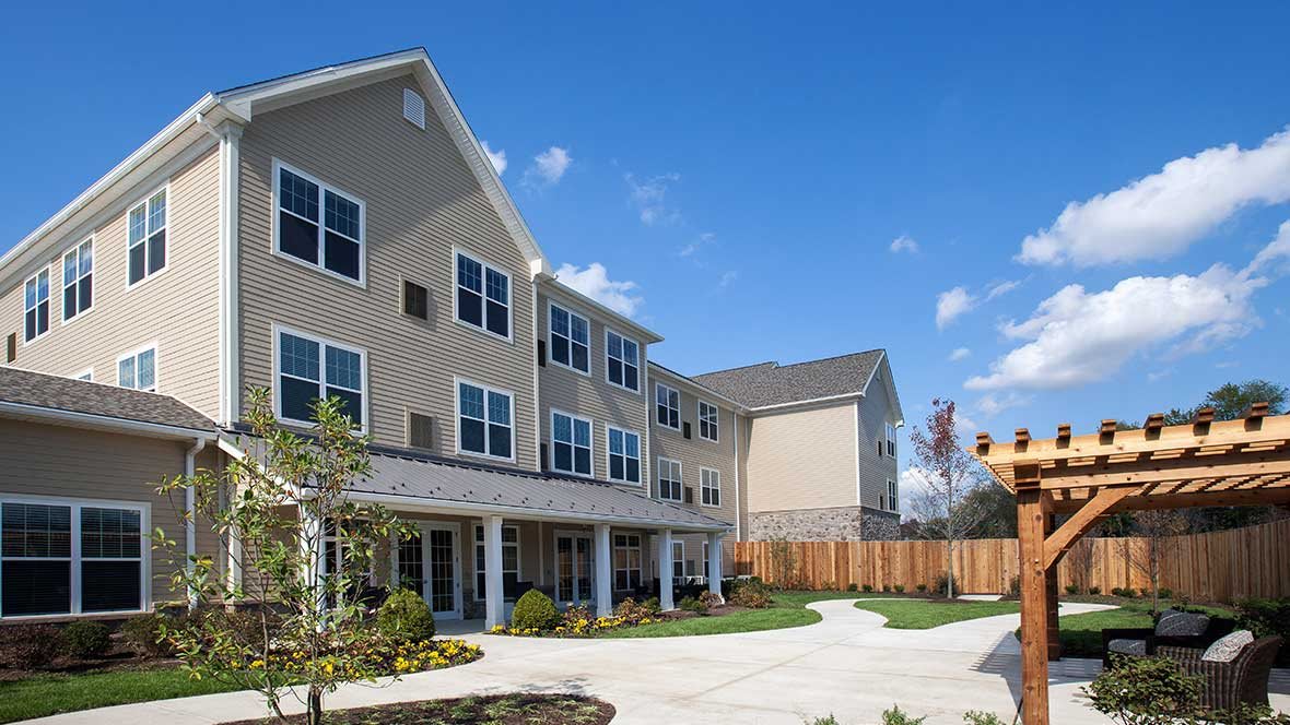 A modern residential apartment building with landscaped surroundings on a sunny day.
