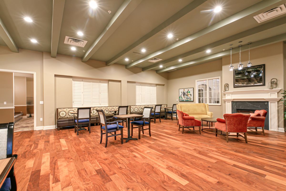 A modern dining area with wood flooring, tables, and ceiling lights.