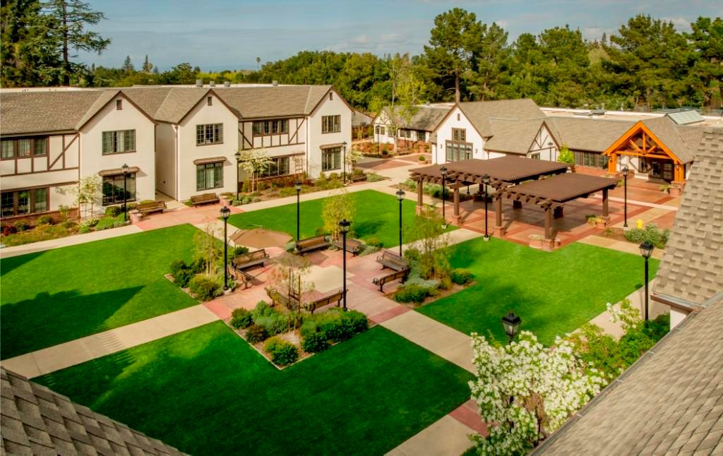 Aerial view of a well-maintained courtyard with buildings, lush gardens, and walking paths.