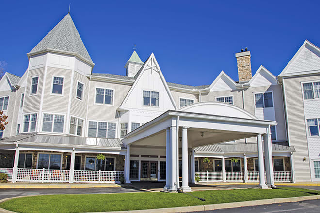 A sunny view of a large building with an entrance porch and multiple windows.