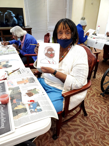 A resident proudly displays her artwork during a creative session in a community center.