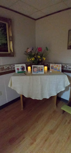 A serene home altar adorned with flowers, candles, and cherished photographs.