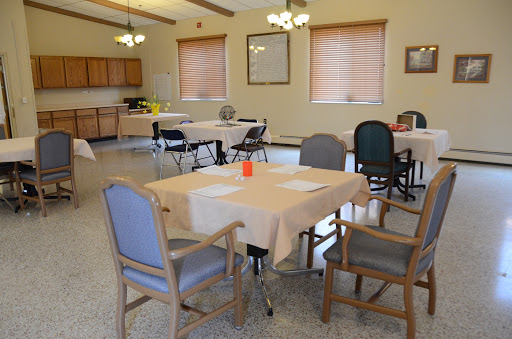 A spacious dining area with neatly arranged tables and chairs, ready for a community gathering.