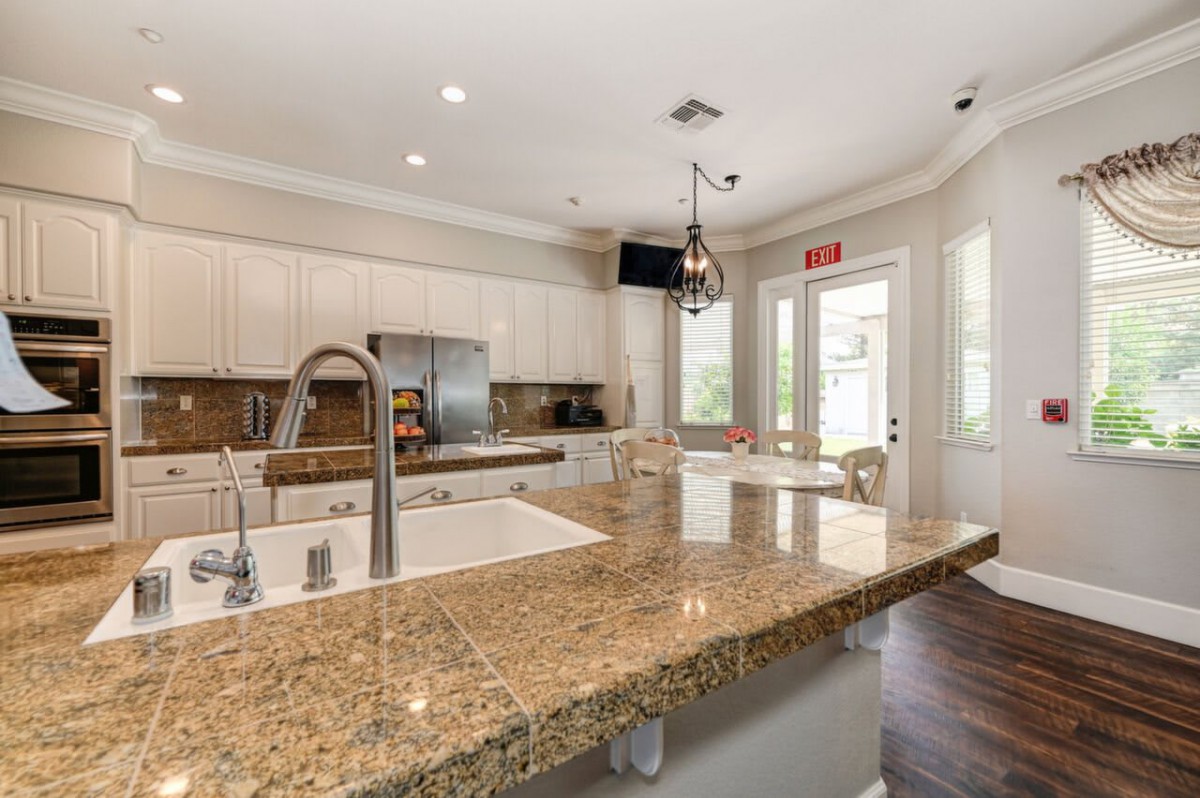 A modern kitchen with a spacious granite island and stainless steel appliances.
