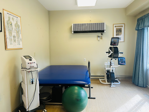 A well-equipped physical therapy room featuring a treatment table, exercise equipment, and a fitness ball.