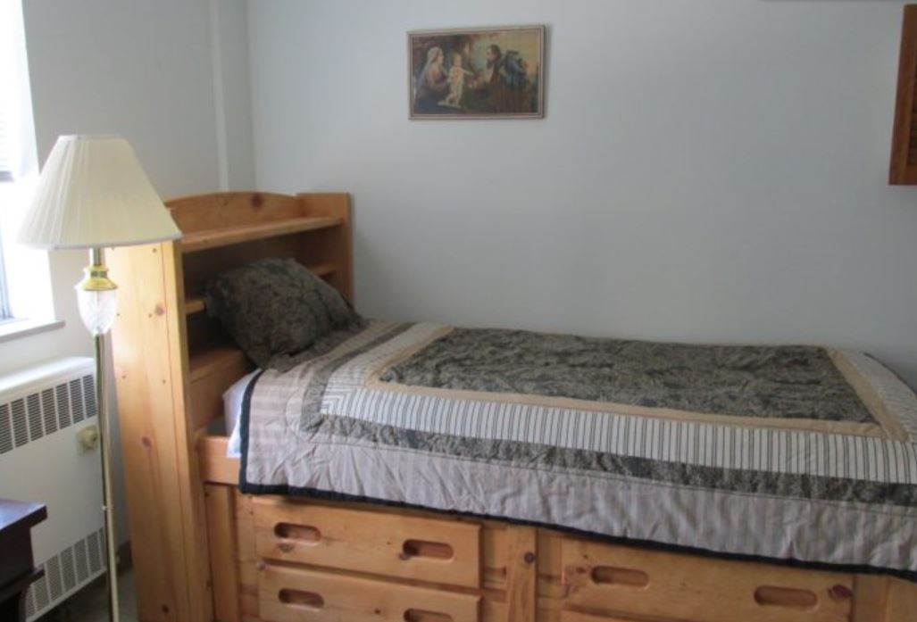 A cozy bedroom with a single wooden bed featuring built-in drawers for storage.