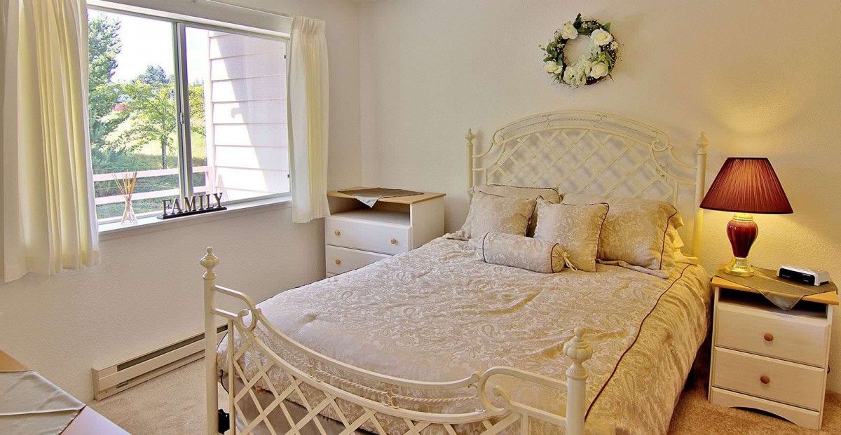 A cozy bedroom with white decor and natural light.