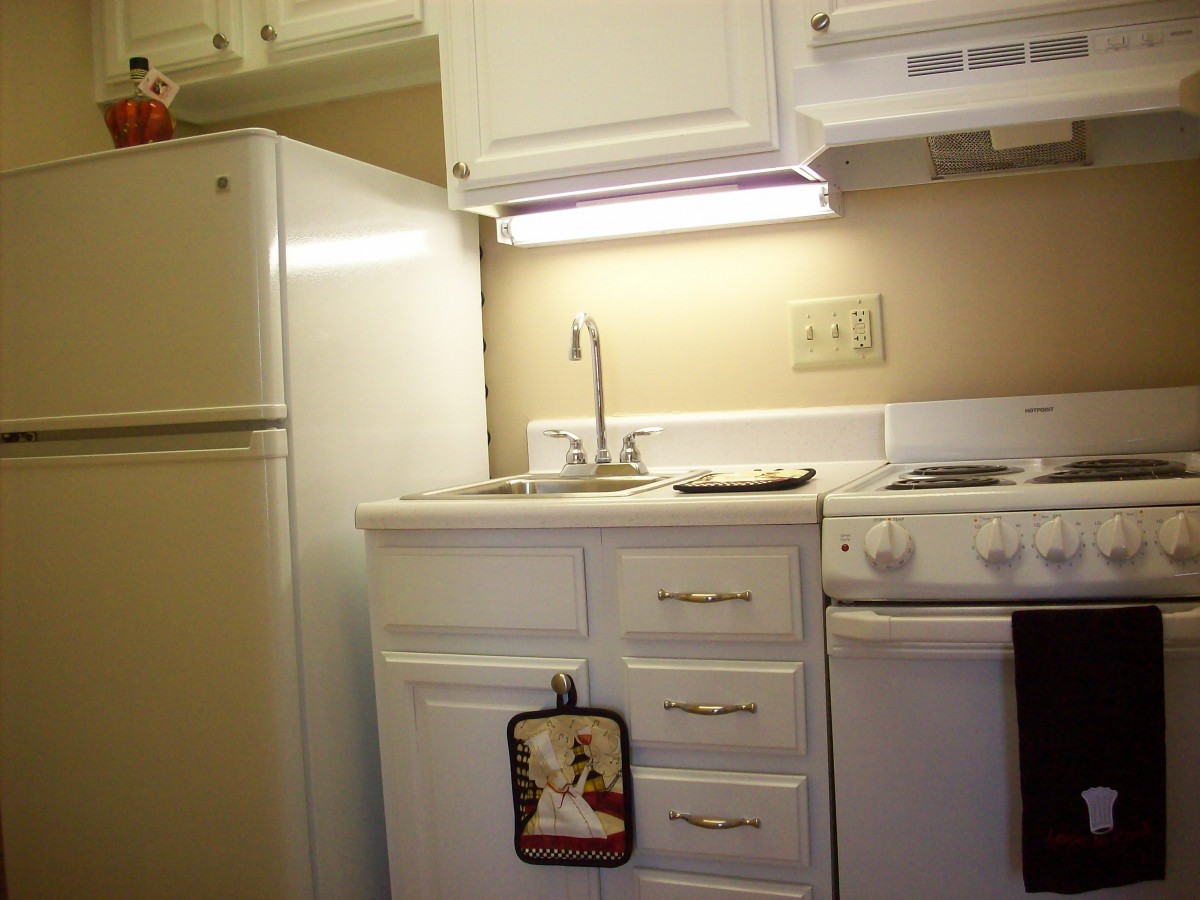 A small, well-organized kitchen with white cabinets, a refrigerator, and a stove.