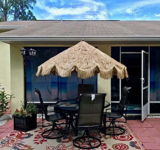 A cozy outdoor patio setup with a round table, chairs, and a fringed umbrella.