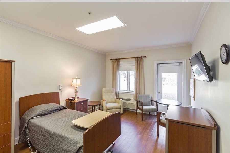 A neatly organized hospital room with a bed, chairs, and a table.