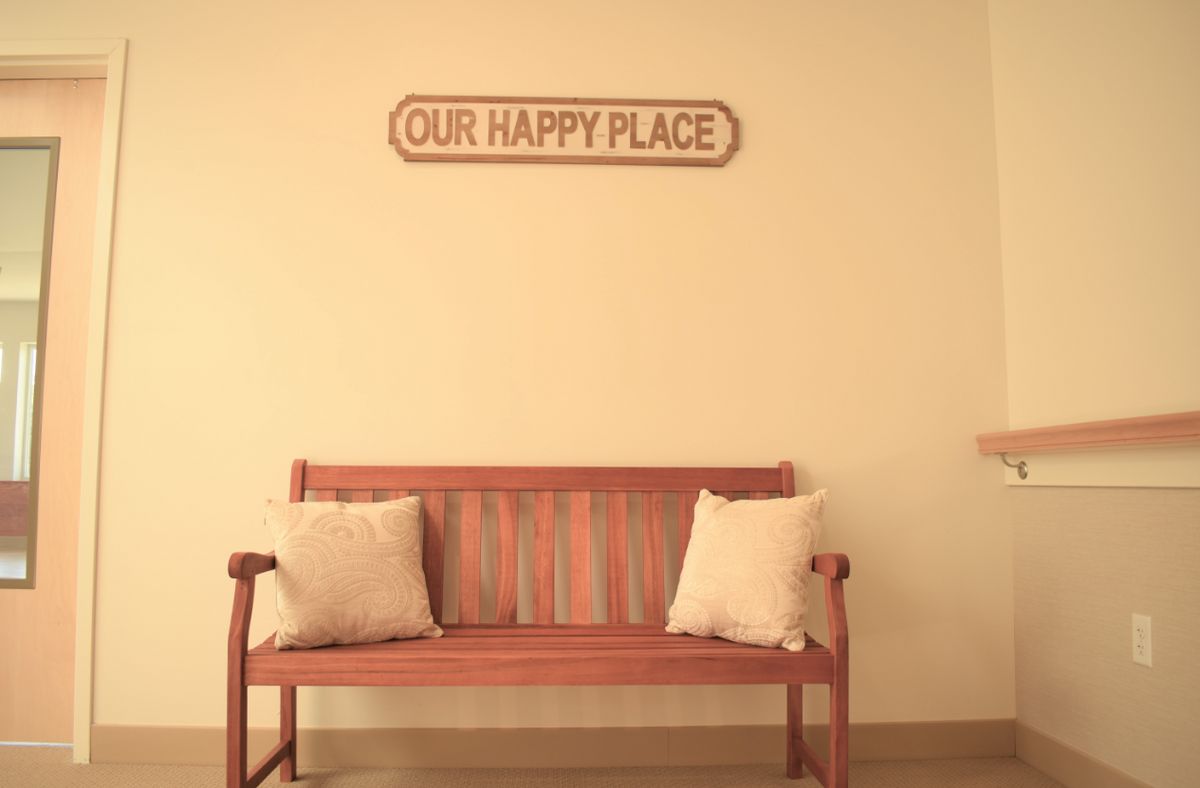 A cozy bench with cushions sits beneath a sign reading 'Our Happy Place'.