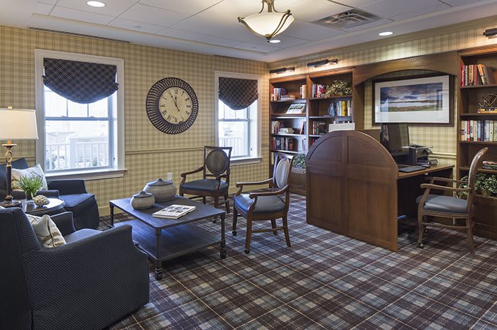 A cozy office space with a bookshelf and a clock on the wall.