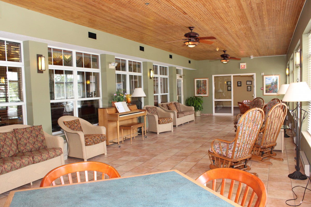 A cozy sunroom with wicker chairs, large windows, and ceiling fans providing a comfortable seating area.