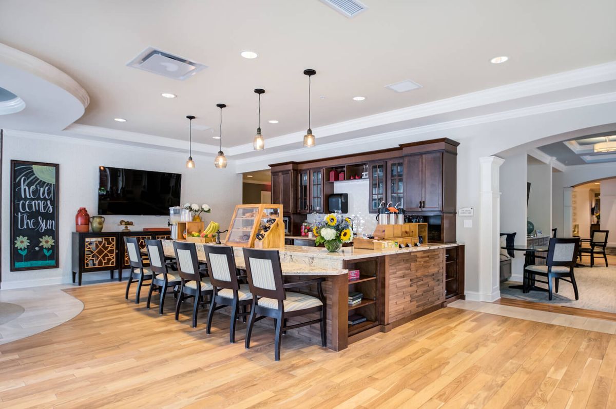 A modern kitchen with a large island and dining area, featuring elegant pendant lighting and sleek wooden cabinetry.