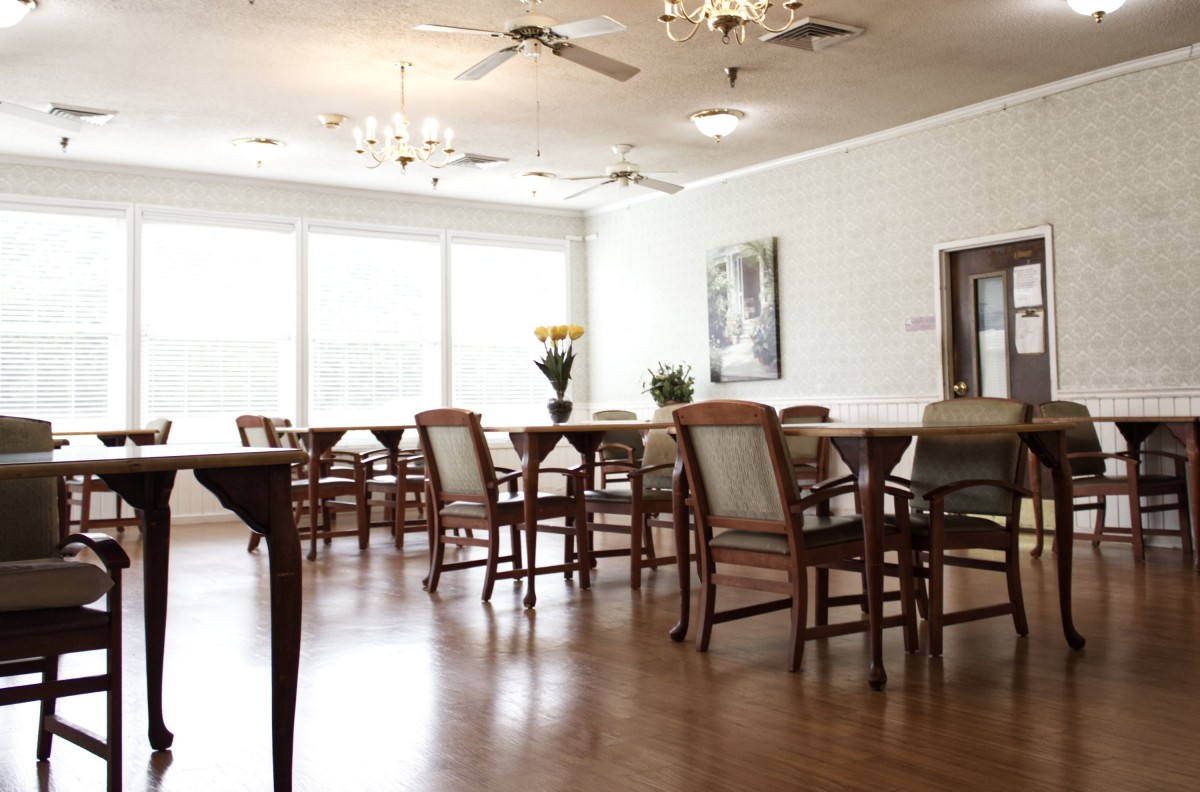 A spacious dining room with wooden furniture and elegant chandeliers.