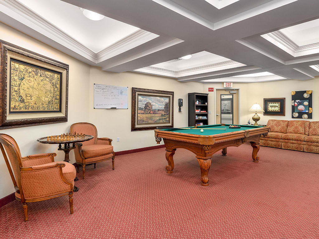 A luxurious billiard room with a pool table, comfortable seating, and elegant decor.