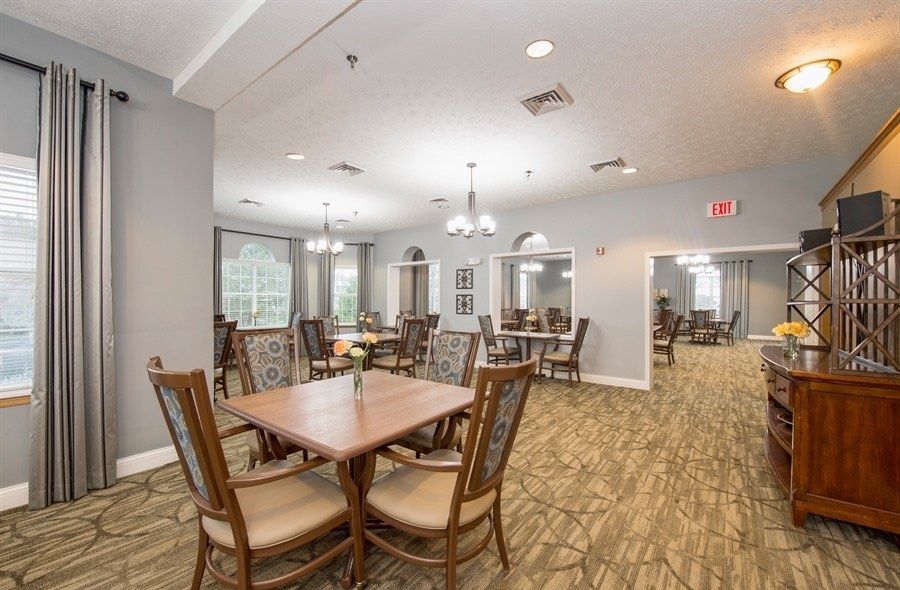 A modern dining area with multiple tables and chairs, well-lit by overhead lights.