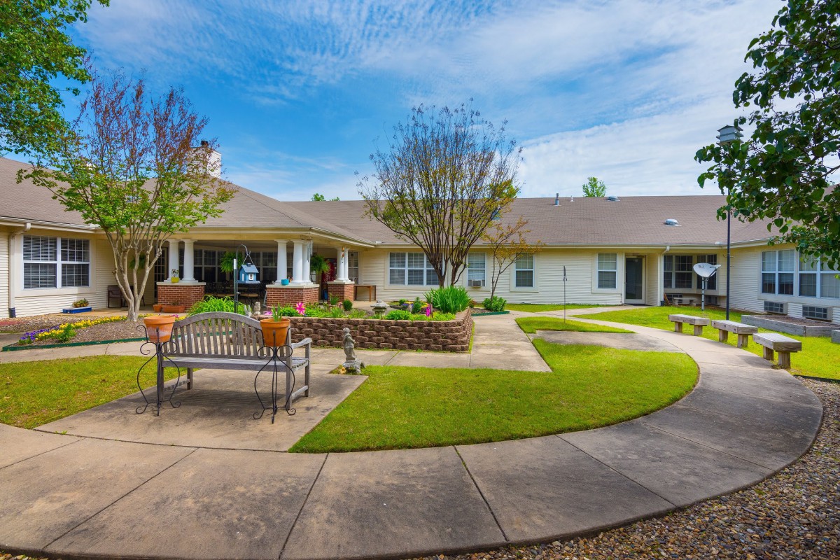 A well-maintained courtyard with a bench, pathways, and landscaping in front of a building.
