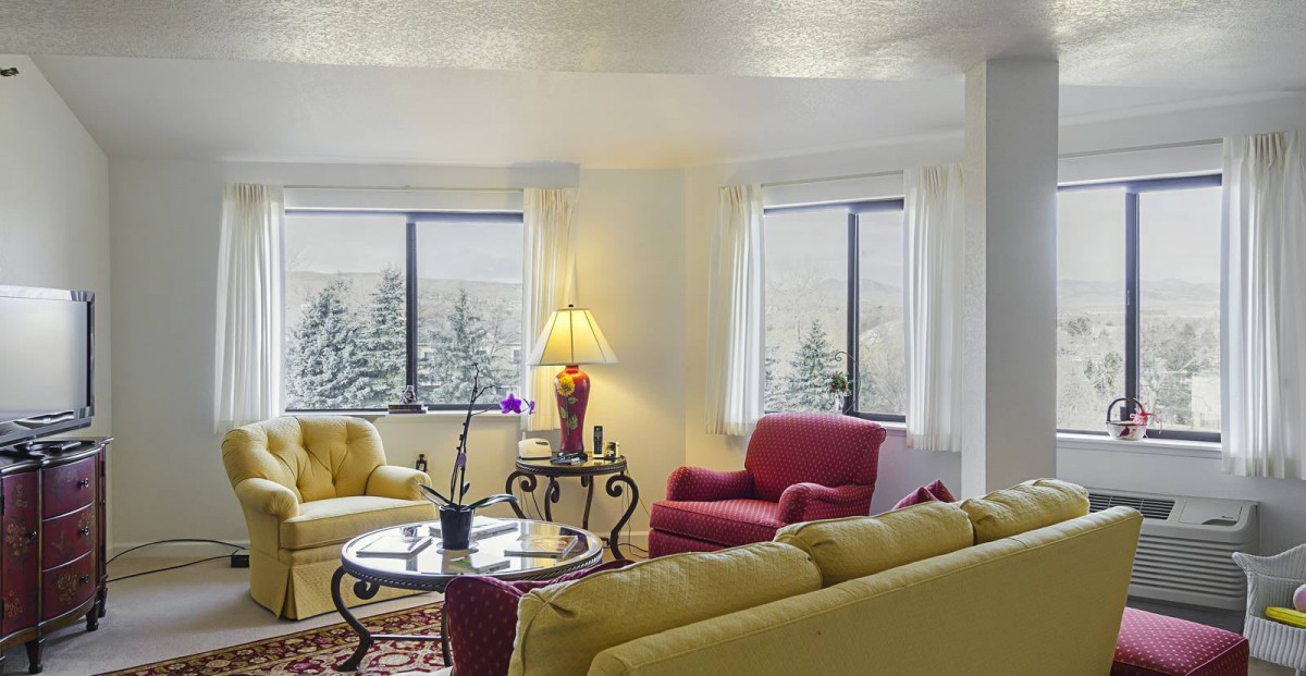 A cozy living room with colorful seating and a view of a snowy landscape outside the windows.