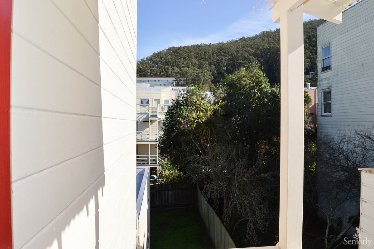 A sunny day view featuring buildings, trees, and a mountainous backdrop.