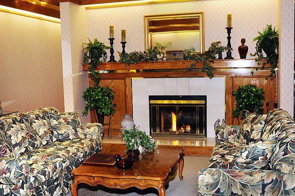 A cozy living room featuring a fireplace with decorative elements, including candles, a mirror, and greenery.