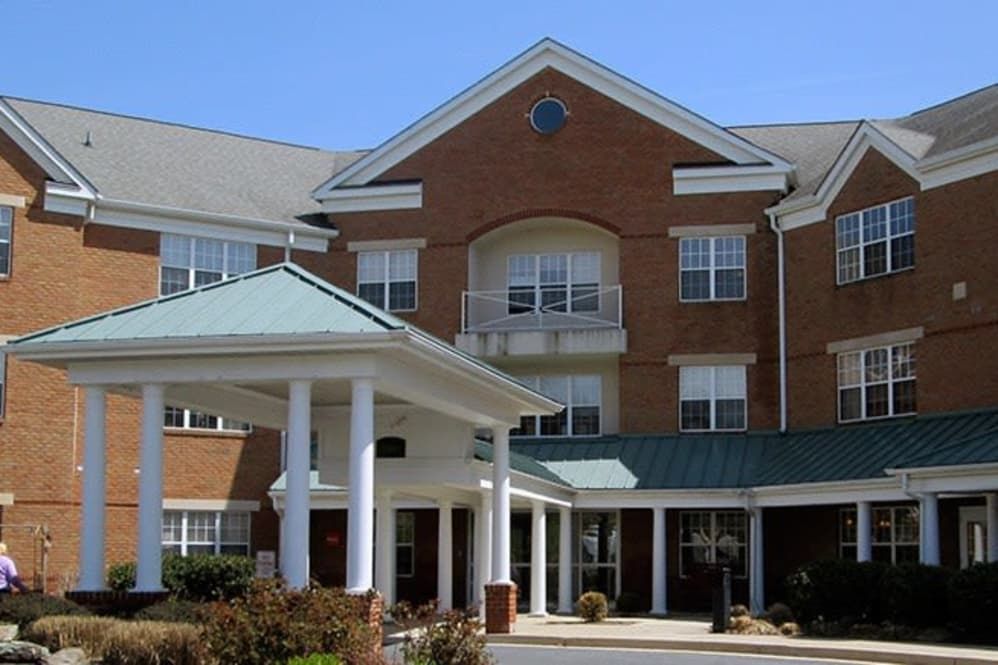 A brick residential building with a prominent entrance and large windows under a clear blue sky.