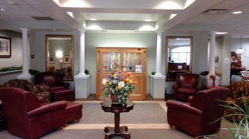 A welcoming lobby area featuring comfortable seating, a floral arrangement, and decorative mirrors.