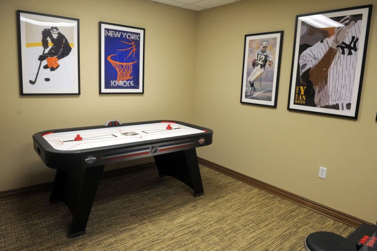 A cozy game room featuring an air hockey table and sports-themed posters on the walls.