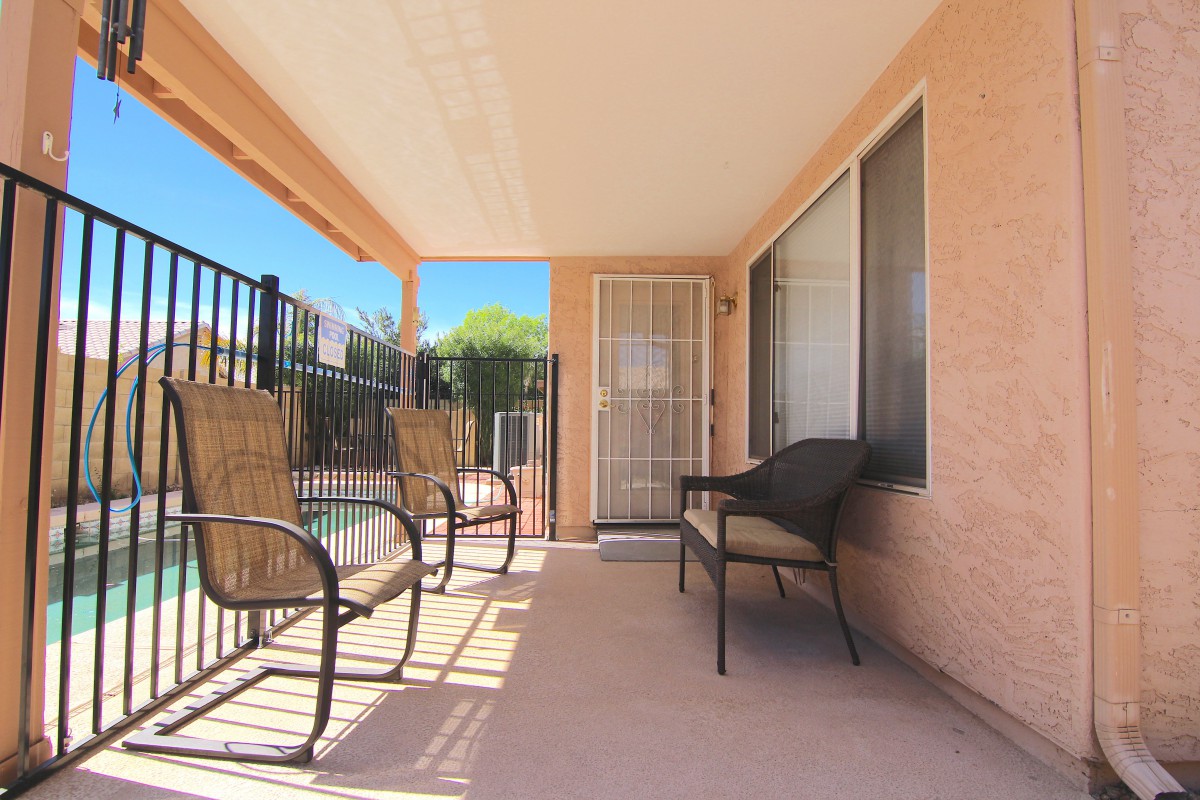 A sunny patio with outdoor seating, including chairs and a bench.