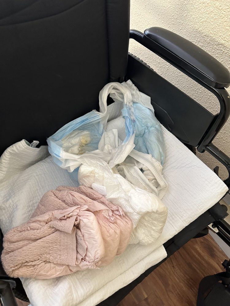 A wheelchair with a plastic bag and some clothes on it.