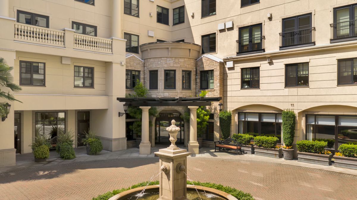 A view of a residential building courtyard featuring an elegant fountain in the center.