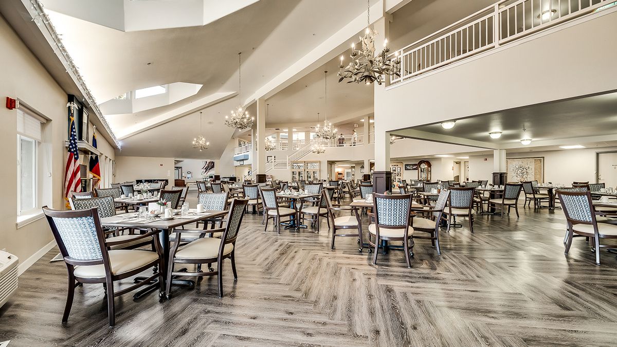A spacious and elegantly designed restaurant interior with neatly arranged tables and chandeliers.