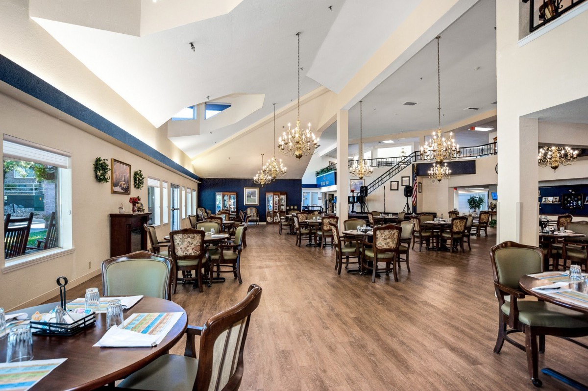 A spacious and elegantly designed dining hall with multiple tables and chandeliers.