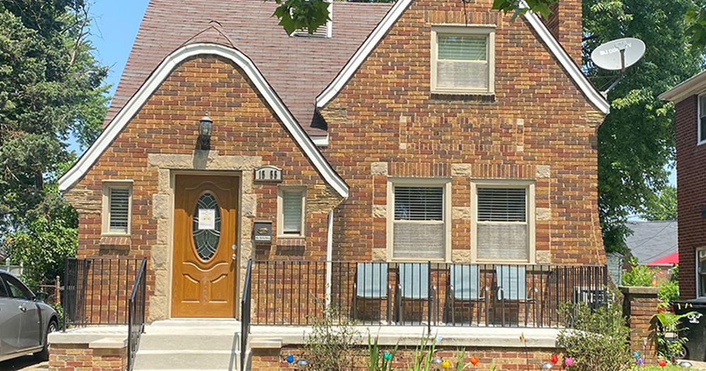 A brick residential house with a unique roof design and a front porch.