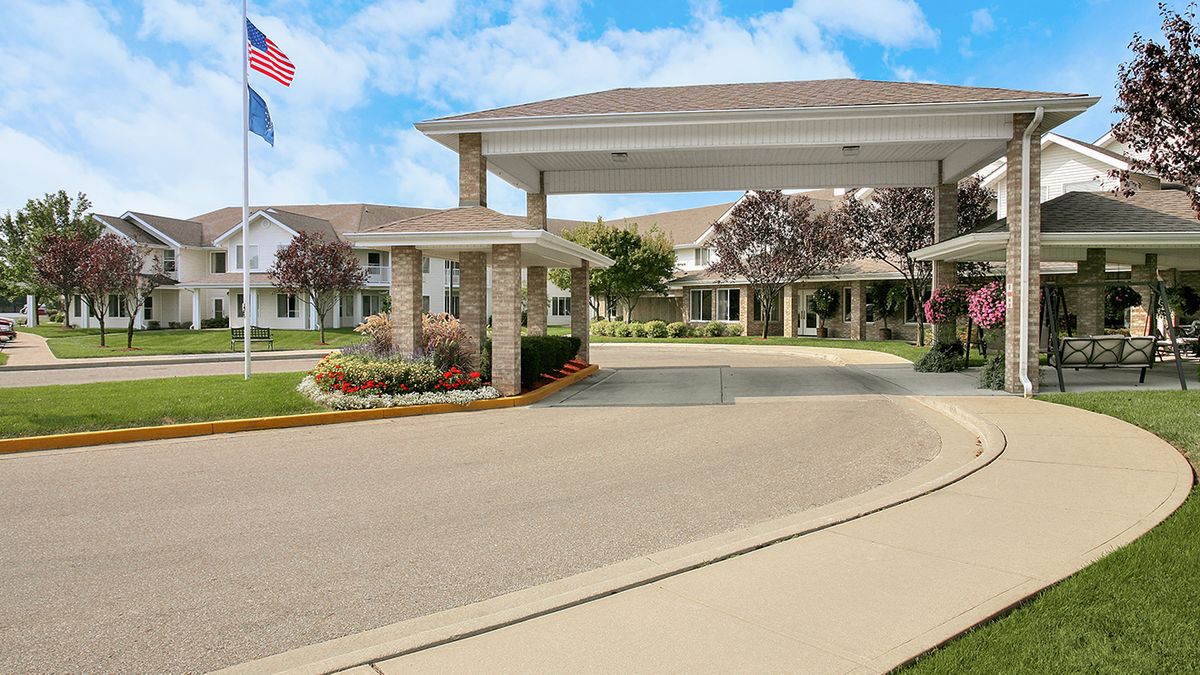 A welcoming entrance with a driveway and landscaped gardens under a sunny sky.