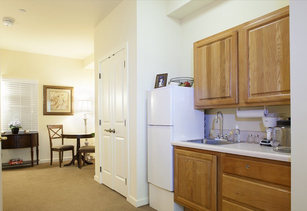 A cozy kitchen with wooden cabinets and a dining area in the background.