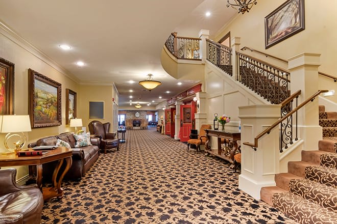 A spacious hotel lobby featuring elegant decor, with a staircase and comfortable seating arrangements.