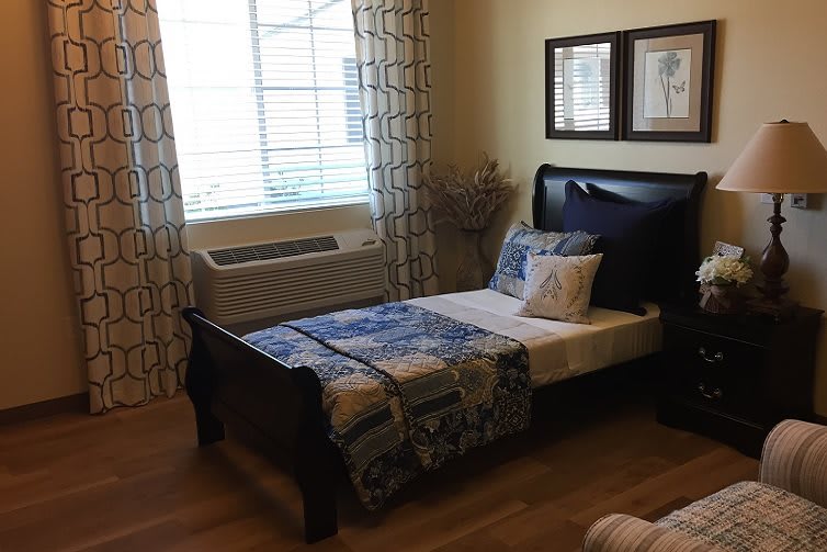 A cozy bedroom with a single bed, wooden floor, and soft natural light from the window.