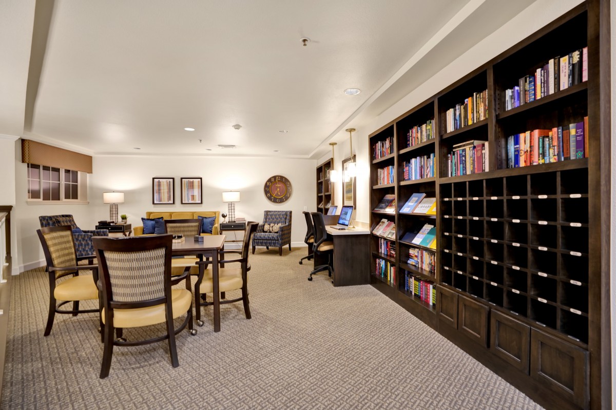 A cozy library space with bookshelves, tables, and chairs for reading and studying.