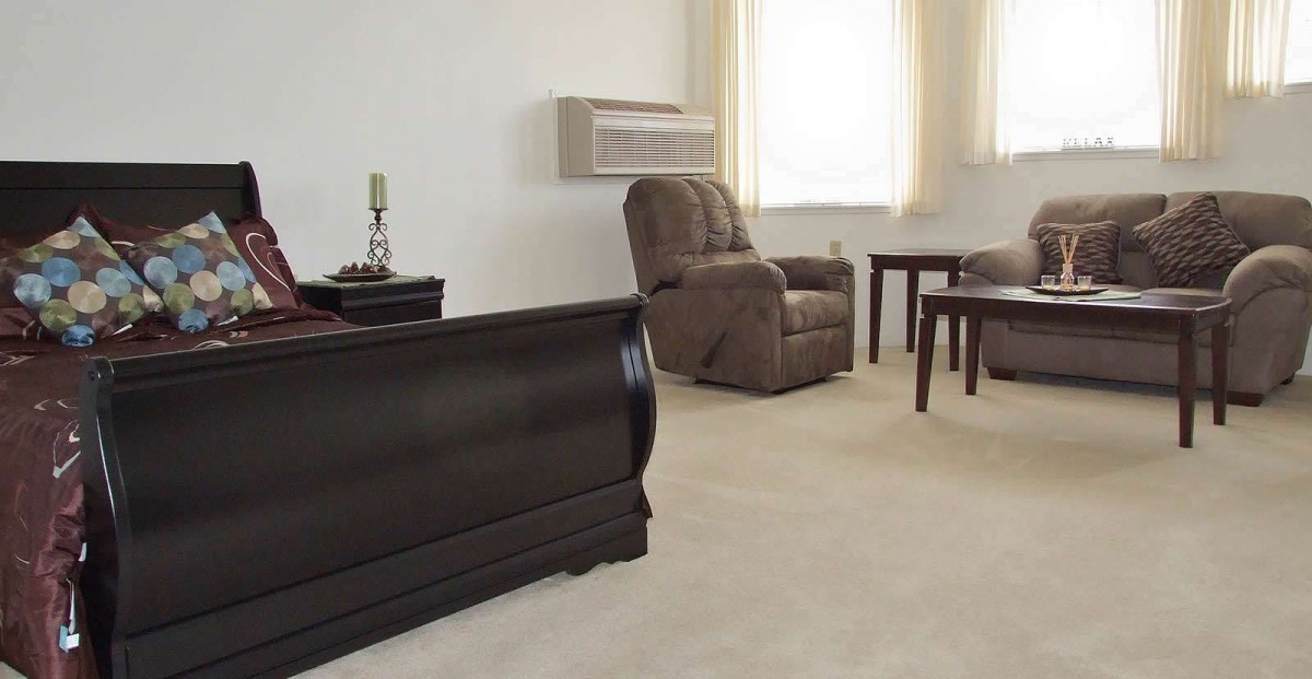 A simple living room with an armchair, coffee table, and wooden chest.