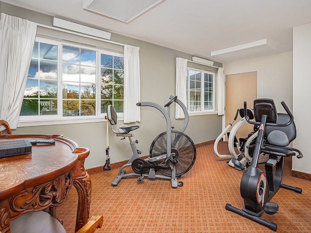 A bright home gym with stationary bikes and exercise equipment.