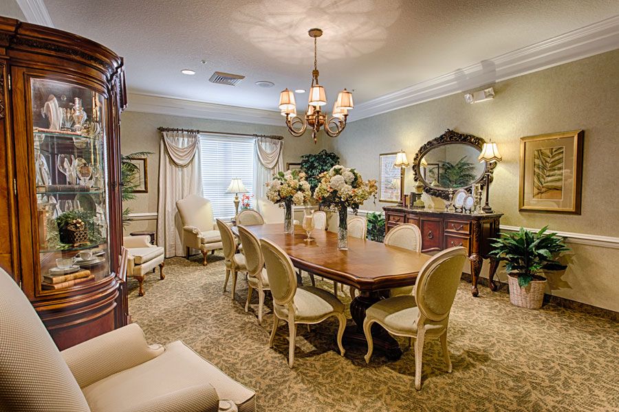 An elegantly decorated dining room with a traditional style, featuring a wooden table and chairs, a chandelier, and floral arrangements.