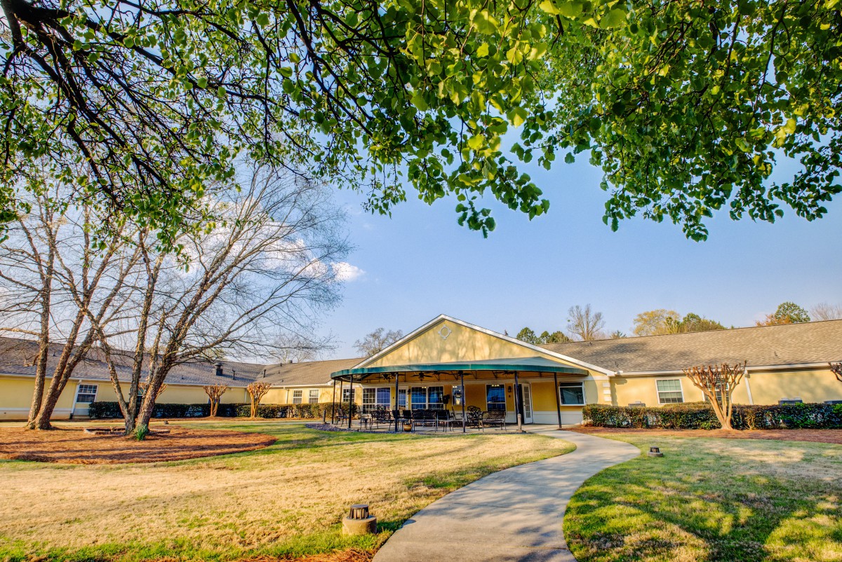 A sunny day view of a school building surrounded by trees and a grassy yard.